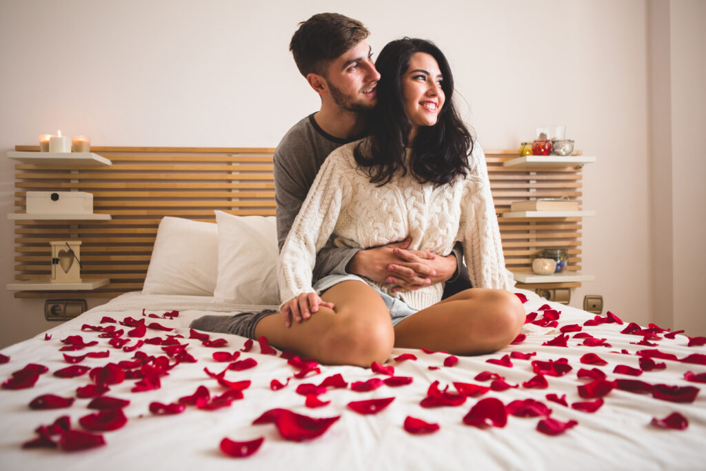 couple-sitting-knees-bed-with-petals